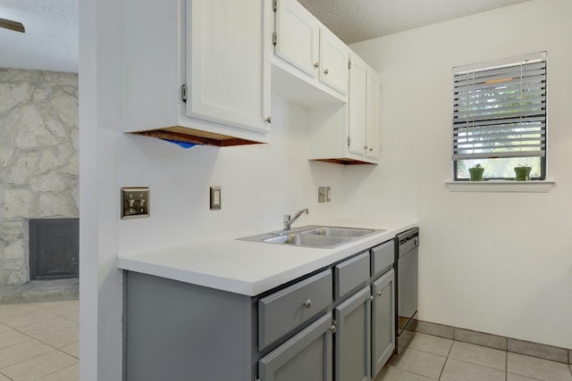 kitchen with light tile floors, gray cabinets, white cabinets, sink, and a textured ceiling