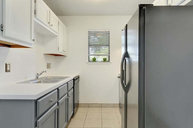 kitchen featuring black fridge, gray cabinetry, white cabinetry, sink, and light tile floors