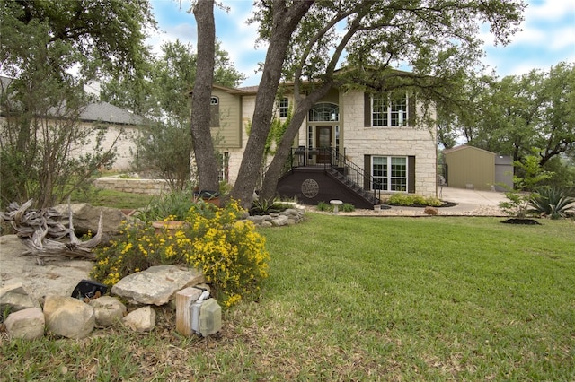 view of front facade featuring a front yard and a storage shed