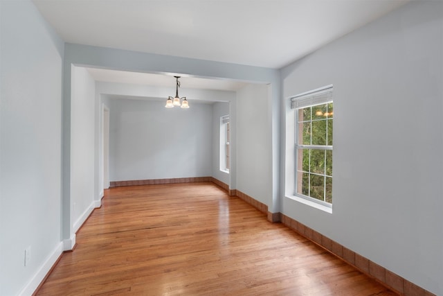 spare room with a chandelier and light hardwood / wood-style flooring