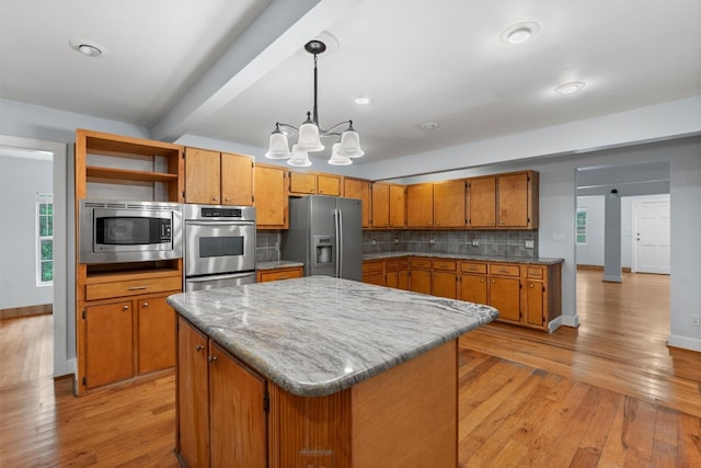 kitchen featuring pendant lighting, tasteful backsplash, light wood-type flooring, and stainless steel appliances