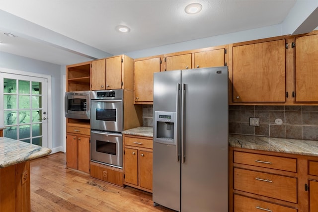 kitchen featuring appliances with stainless steel finishes, light wood-type flooring, and backsplash