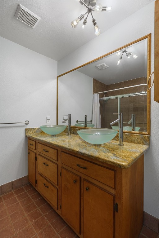 bathroom with tile flooring, a textured ceiling, and double sink vanity