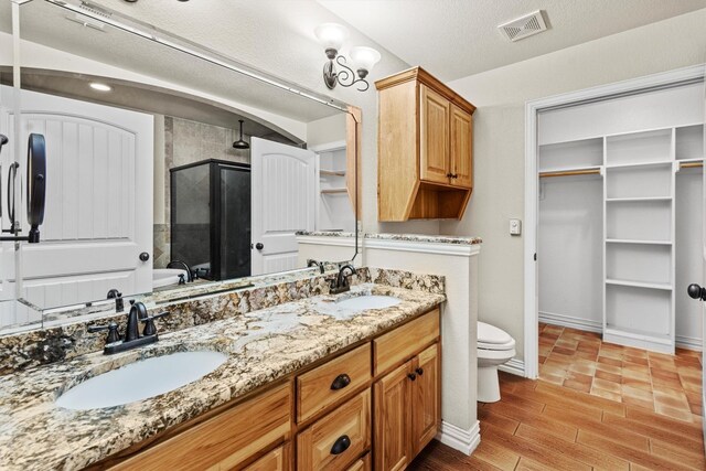 bathroom with oversized vanity, a washtub, toilet, a textured ceiling, and double sink