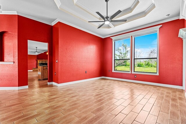 unfurnished room featuring light hardwood / wood-style floors, ceiling fan, crown molding, and a raised ceiling