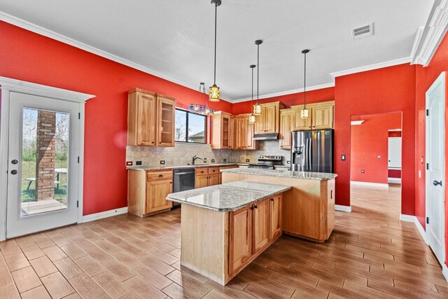 kitchen featuring a wealth of natural light, appliances with stainless steel finishes, a center island, and light stone countertops