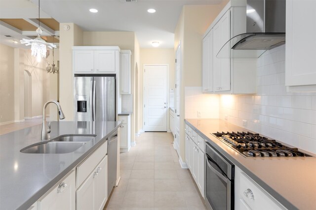 kitchen featuring appliances with stainless steel finishes, backsplash, wall chimney range hood, white cabinets, and sink