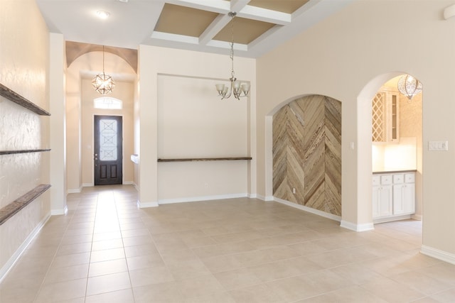 tiled foyer featuring beam ceiling, coffered ceiling, and a chandelier