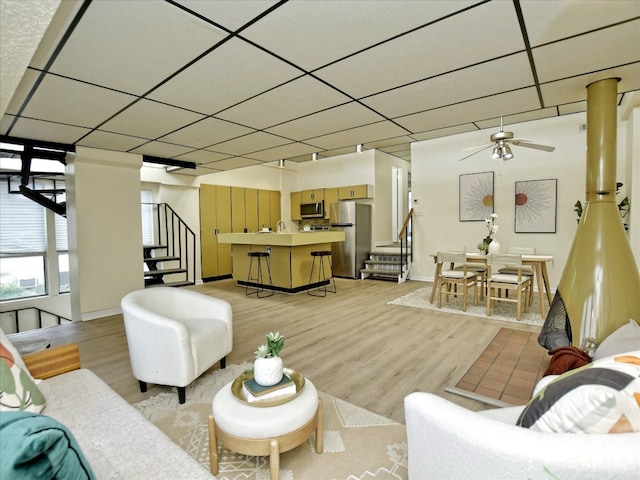 living room featuring a paneled ceiling, light wood-type flooring, and ceiling fan