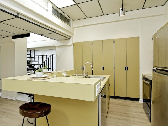 kitchen with a center island with sink, light wood-type flooring, electric range, a drop ceiling, and sink