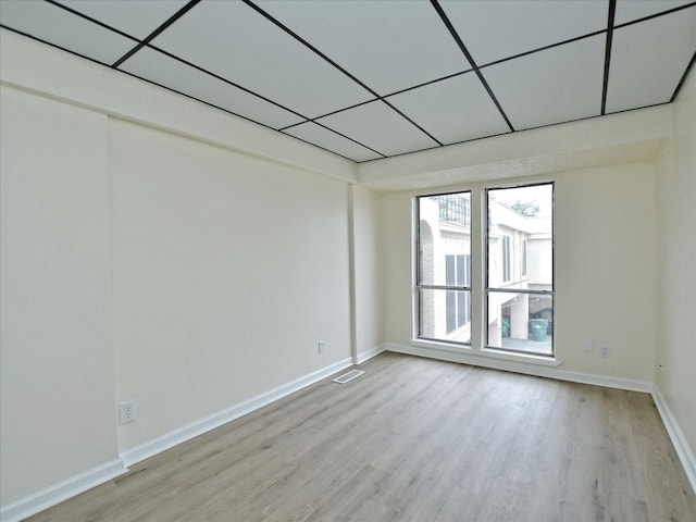 empty room with a paneled ceiling and light hardwood / wood-style flooring