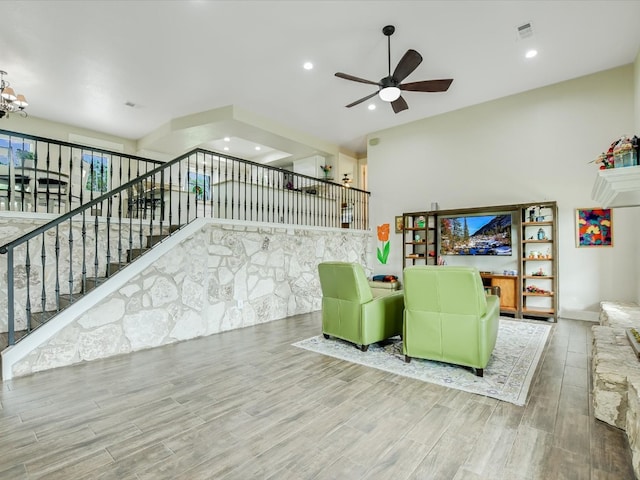 living room with ceiling fan with notable chandelier and light hardwood / wood-style floors