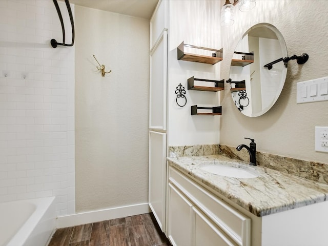 bathroom with hardwood / wood-style flooring, tiled shower / bath, and large vanity