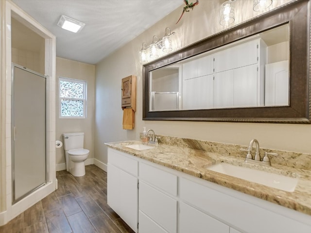 bathroom with walk in shower, vanity with extensive cabinet space, wood-type flooring, dual sinks, and toilet