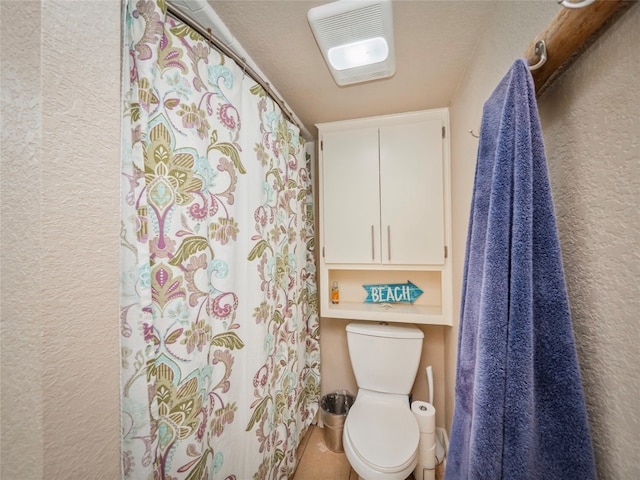 bathroom with toilet and a textured ceiling