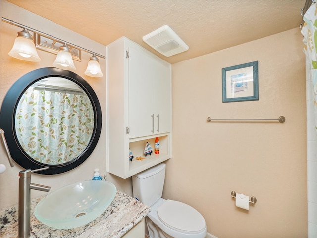 bathroom featuring vanity with extensive cabinet space, toilet, and a textured ceiling