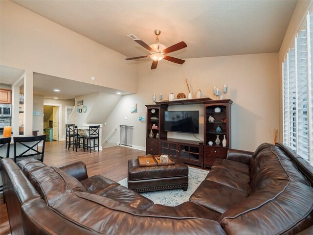 living area featuring ceiling fan, baseboards, and wood finished floors