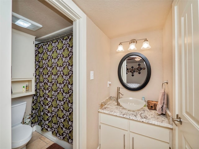 bathroom with tile flooring, vanity, toilet, and a textured ceiling