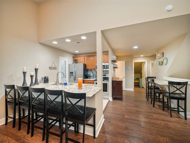 kitchen featuring dark hardwood / wood-style flooring, appliances with stainless steel finishes, a kitchen breakfast bar, and sink