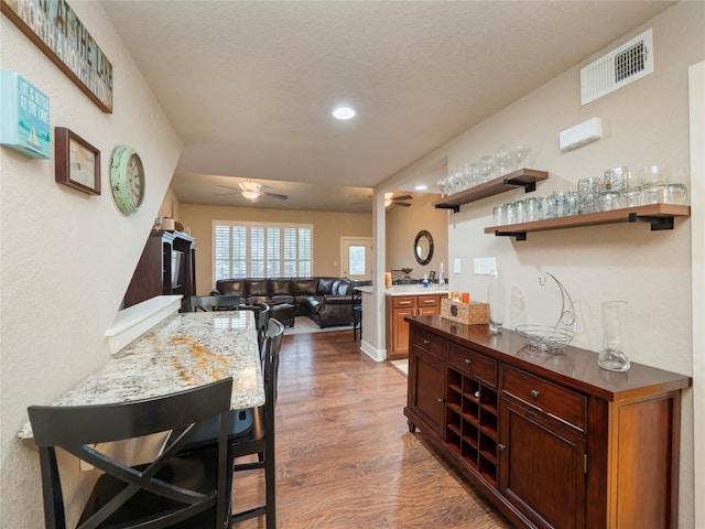 kitchen with open shelves, visible vents, a ceiling fan, open floor plan, and wood finished floors