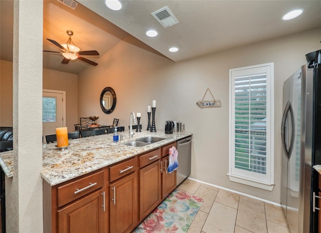 kitchen featuring light stone counters, appliances with stainless steel finishes, light tile floors, sink, and ceiling fan