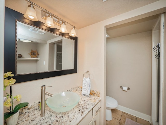 bathroom with a textured ceiling, oversized vanity, tile floors, and toilet