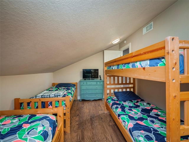 bedroom with dark hardwood / wood-style floors, vaulted ceiling, and a textured ceiling