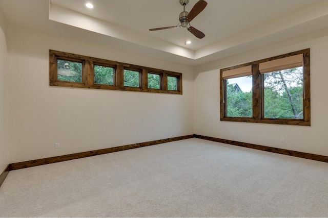 carpeted empty room with a raised ceiling and ceiling fan