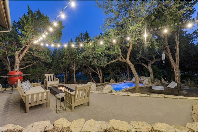 patio at night with a pool and an outdoor fire pit