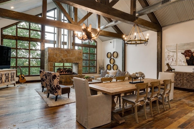 dining room with hardwood / wood-style flooring, high vaulted ceiling, a notable chandelier, beamed ceiling, and a stone fireplace