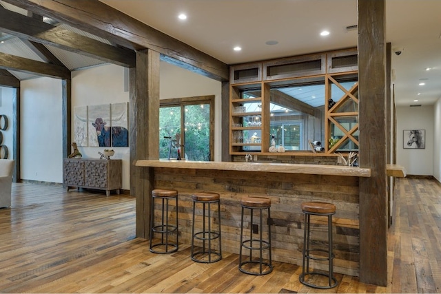 bar with lofted ceiling and hardwood / wood-style flooring