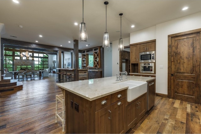 kitchen with a kitchen island with sink, sink, stainless steel appliances, and dark hardwood / wood-style floors