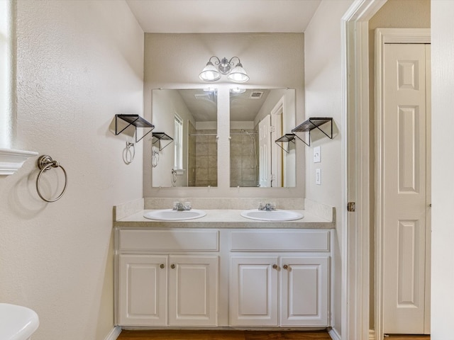 bathroom with toilet and dual bowl vanity