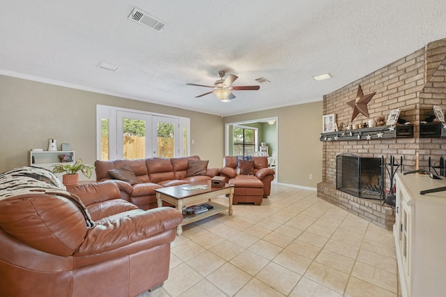 living room with ceiling fan, a brick fireplace, light tile floors, a textured ceiling, and brick wall