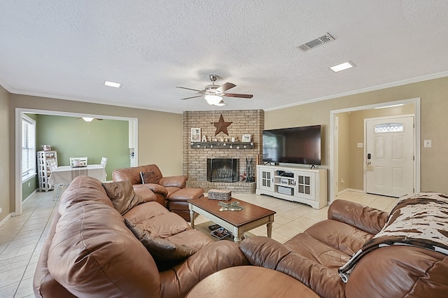 tiled living room featuring ornamental molding, ceiling fan, a textured ceiling, and a fireplace