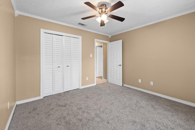 unfurnished bedroom with crown molding, ceiling fan, carpet flooring, a textured ceiling, and a closet