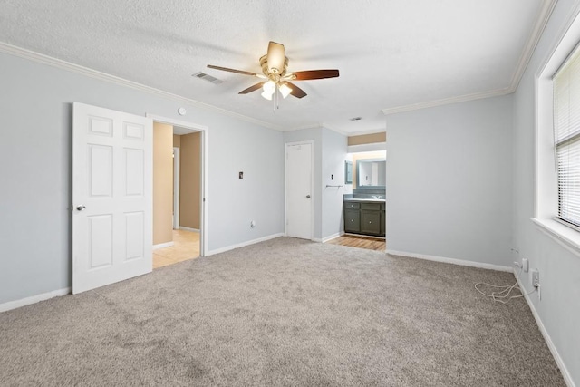 unfurnished bedroom featuring ensuite bath, light colored carpet, ceiling fan, crown molding, and a textured ceiling