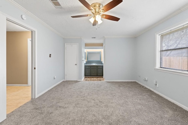 unfurnished bedroom featuring connected bathroom, light carpet, a textured ceiling, ornamental molding, and ceiling fan