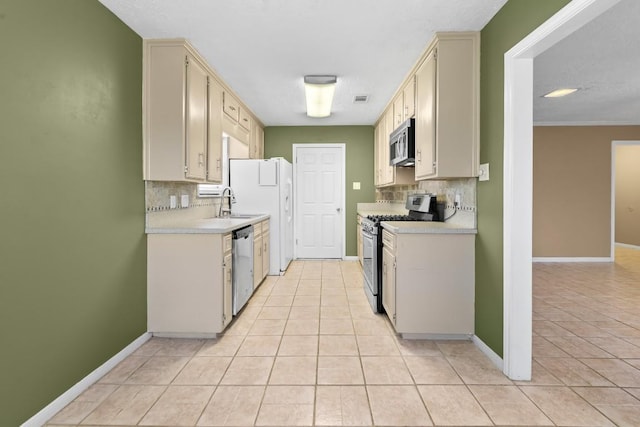 kitchen with light tile patterned flooring, appliances with stainless steel finishes, and cream cabinetry