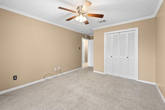 unfurnished bedroom with crown molding, carpet, ceiling fan, and a closet