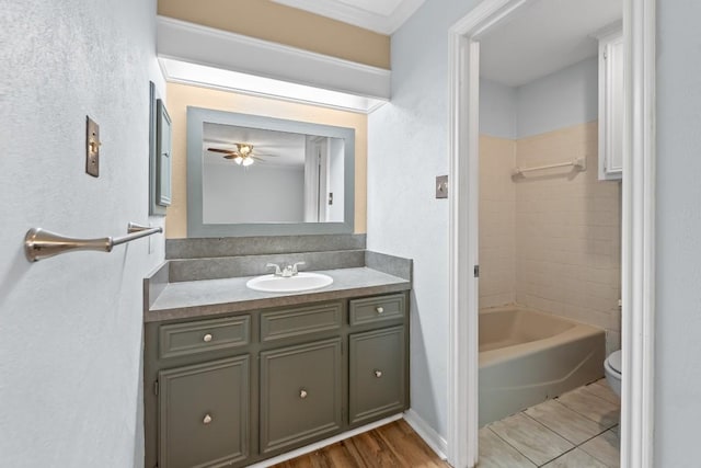 full bathroom featuring ceiling fan, tiled shower / bath, vanity, and toilet