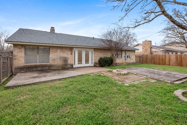 back of property with a yard, a deck, and french doors