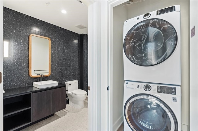 washroom featuring laundry area, recessed lighting, a sink, and stacked washer / drying machine