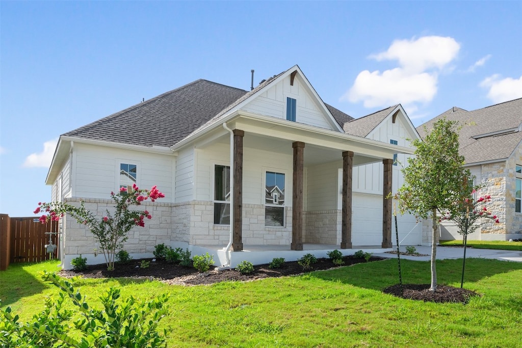 view of front of house featuring a garage, covered porch, and a front lawn