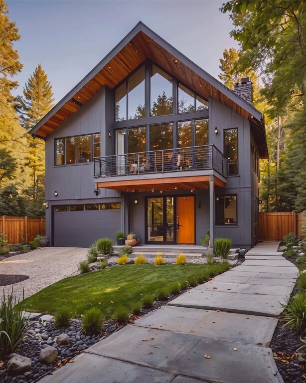 modern home featuring a garage, a balcony, and a front lawn