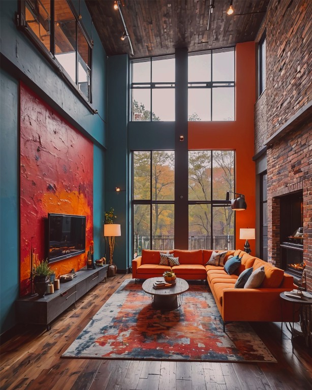 living room featuring hardwood / wood-style flooring, a towering ceiling, rail lighting, and a tiled fireplace