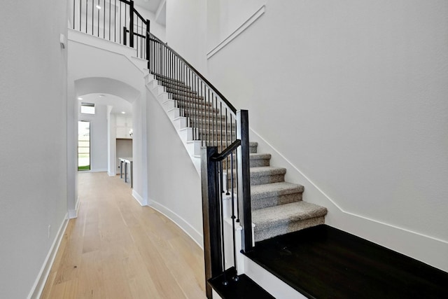 stairway featuring a towering ceiling and hardwood / wood-style floors