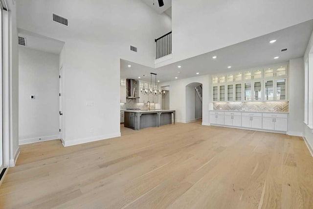 unfurnished living room with light hardwood / wood-style flooring and a high ceiling