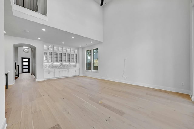 unfurnished living room featuring a towering ceiling and light hardwood / wood-style floors