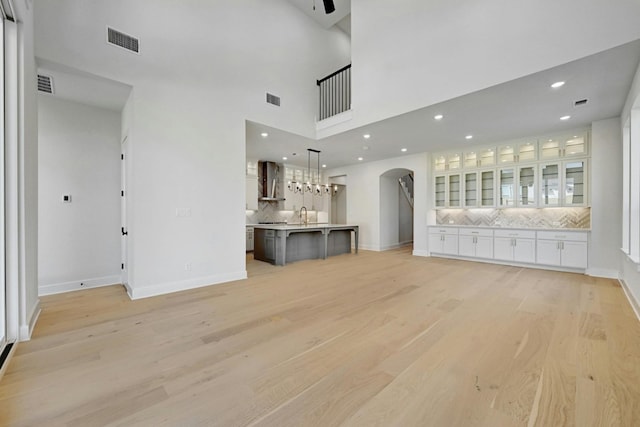 unfurnished living room with a high ceiling and light wood-type flooring